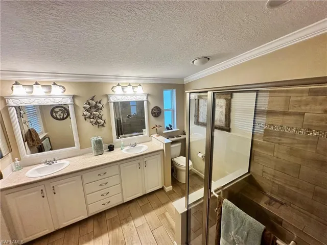 Bathroom featuring vanity, toilet, an enclosed shower, crown molding, and hardwood / wood-style floors