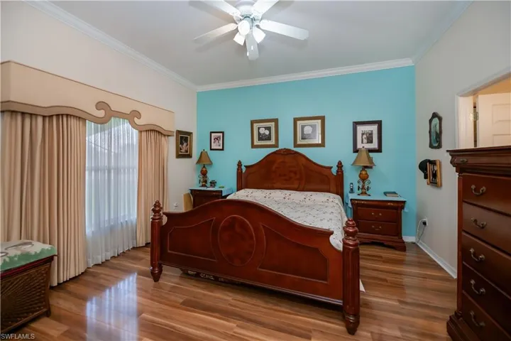 Bedroom with crown molding, wood finished floors, ceiling fan, and baseboards