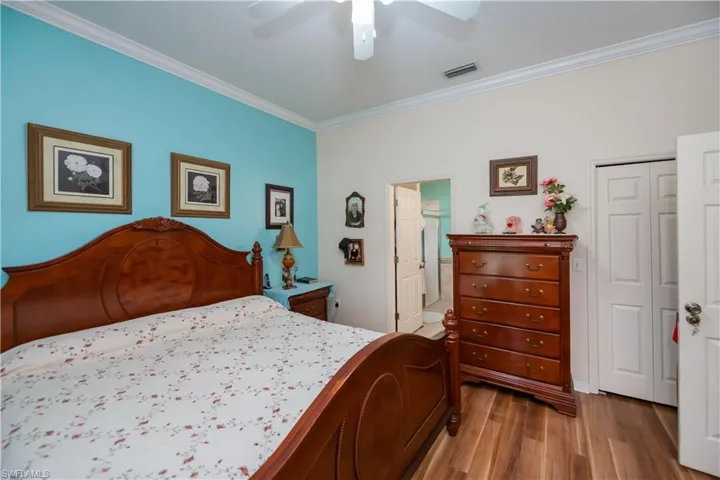 Bedroom with ornamental molding, wood finished floors, a closet, and a ceiling fan