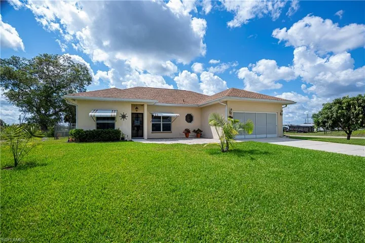 Ranch-style home featuring stucco siding, a front lawn, concrete driveway, and a garage