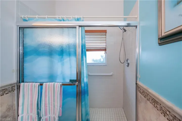 Full bath featuring a stall shower, a wainscoted wall, and tile walls