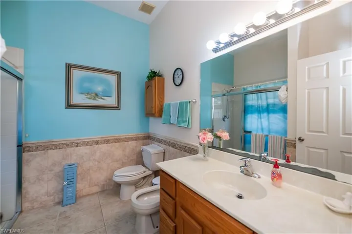 Full bath featuring tile walls, tile patterned floors, a stall shower, toilet, and a bidet