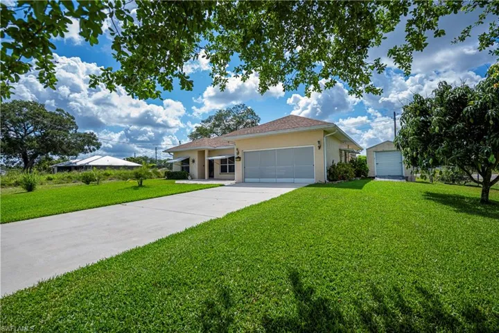 Single story home featuring stucco siding, a front yard, concrete driveway, and a garage