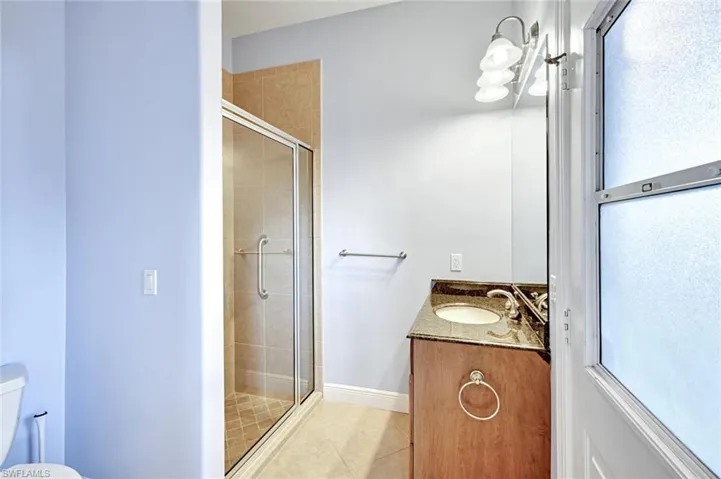 Bathroom with vanity, a shower stall, and light tile patterned floors