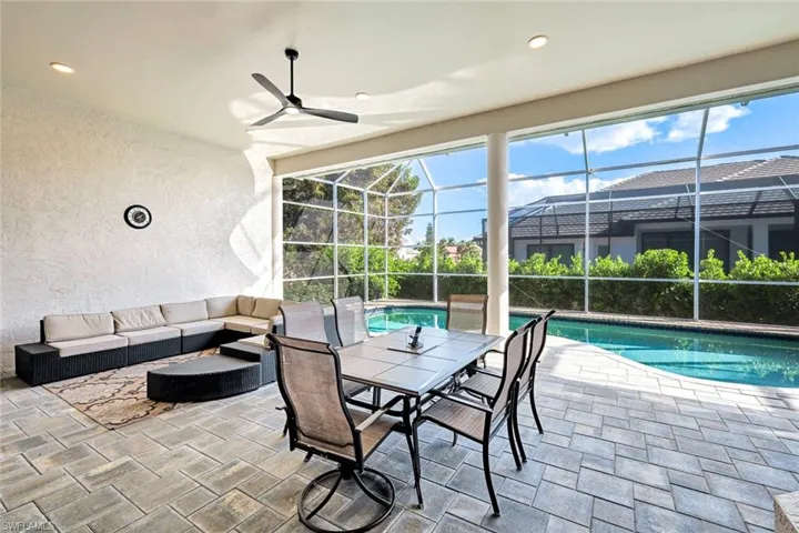 View of patio featuring glass enclosure, a sunroom, an outdoor pool, and an outdoor living space