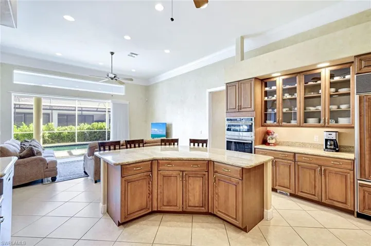 Kitchen featuring brown cabinets, ornamental molding, open floor plan, a ceiling fan, and light tile patterned floors