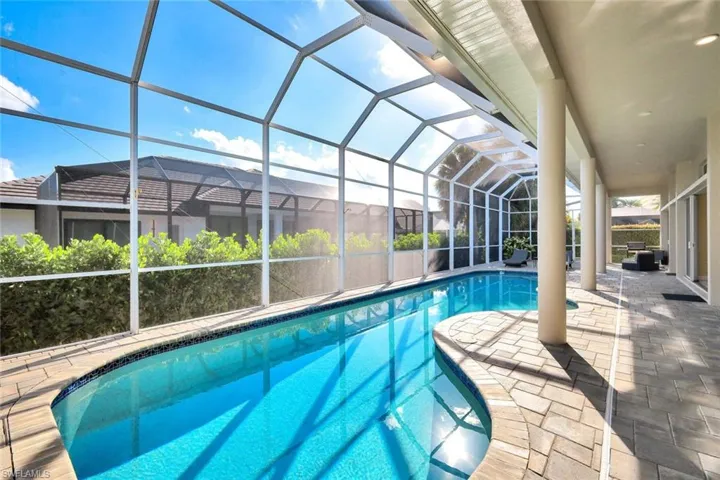 Outdoor pool featuring glass enclosure, a sunroom, and a patio area