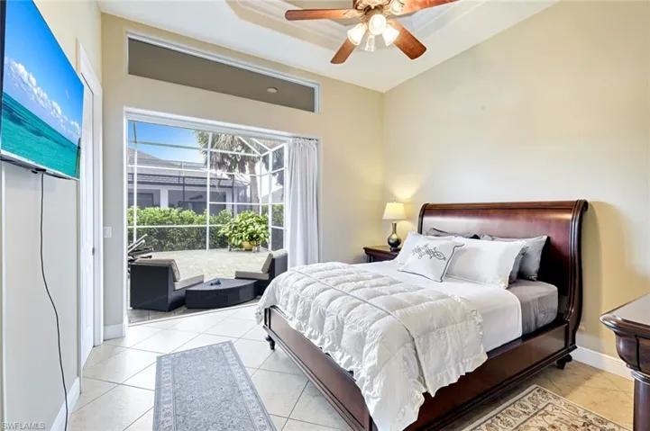 Bedroom with ceiling fan, light tile patterned flooring, and access to exterior