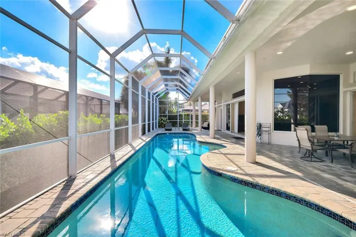 Outdoor pool featuring a sunroom, glass enclosure, and a patio