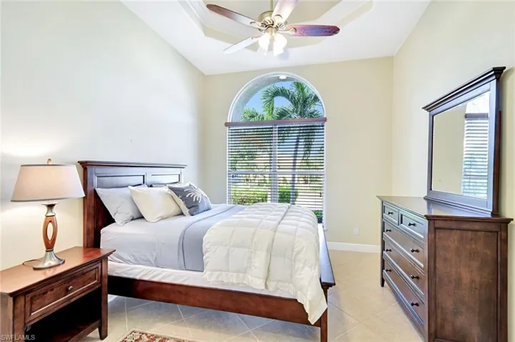 Bedroom with multiple windows, light tile patterned floors, and a ceiling fan