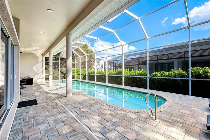 Swimming pool with glass enclosure, a sunroom, and a patio