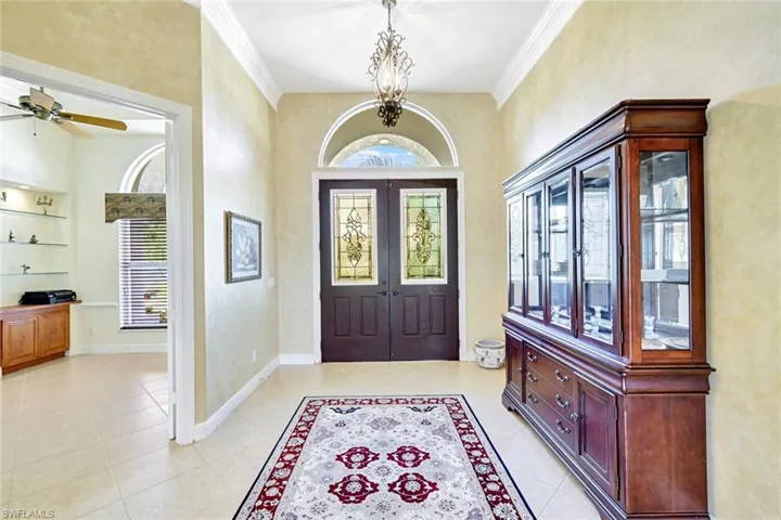 Foyer entrance featuring ornamental molding, a chandelier, and light tile patterned floors