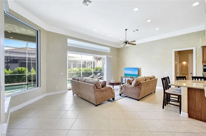 Living room with ornamental molding, light tile patterned floors, recessed lighting, and a ceiling fan