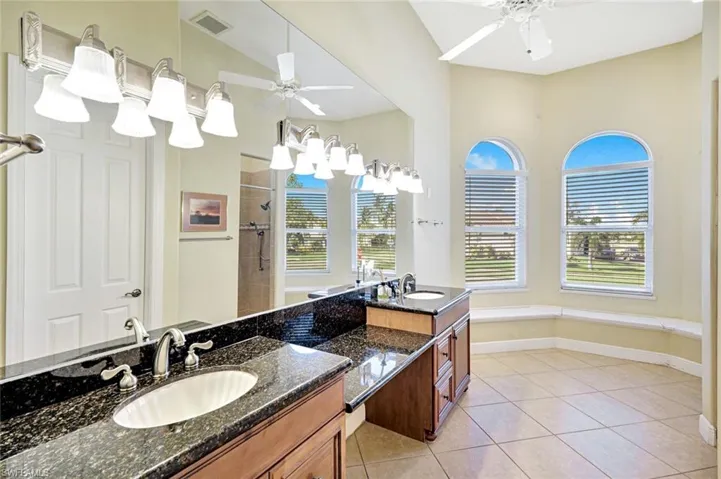 Full bath featuring two vanities, double vanity, a shower stall, light tile patterned floors, and a garden tub