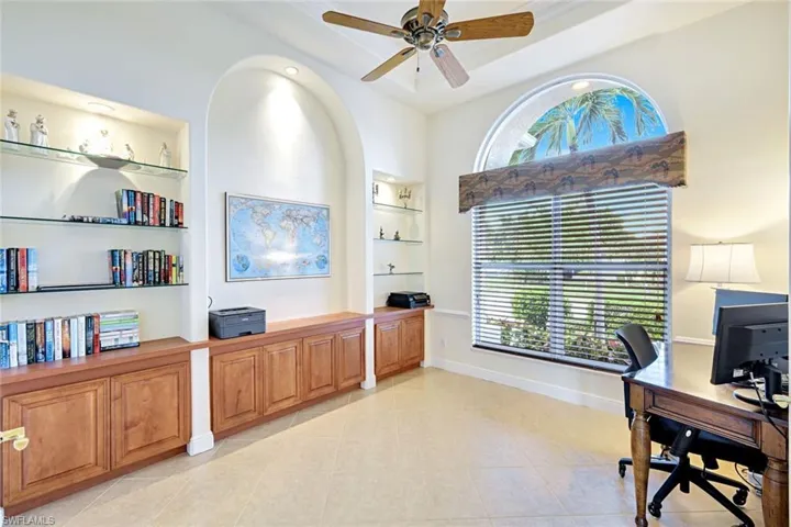 Home office with built in shelves, ceiling fan, and light tile patterned flooring