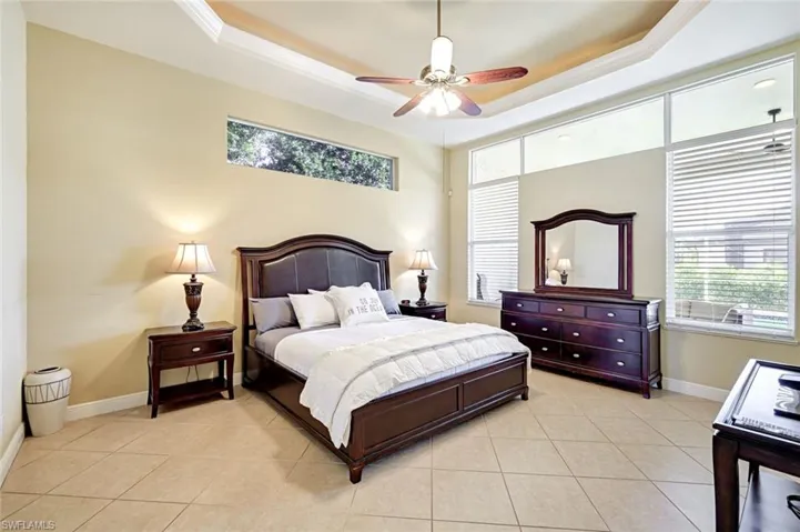 Bedroom featuring a tray ceiling, light tile patterned floors, and a ceiling fan