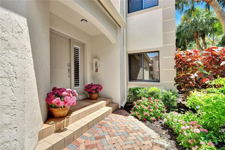 Entryway featuring a light-colored door with a vertical louvered window insert, complemented by a covered porch with an integrated overhead light fixture