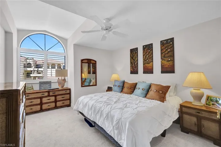 Spacious room featuring a vaulted ceiling and a large arched window with plantation shutters