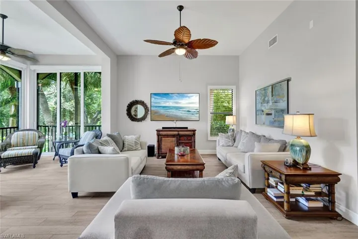 Bright living area featuring wood-finish flooring, vaulted ceilings, and a large sliding glass door opening to a balcony