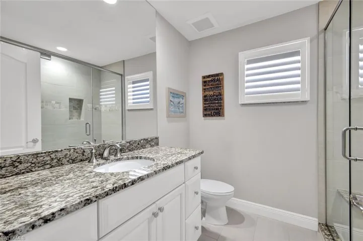 Bathroom vanity with a speckled countertop, undermount sink, and chrome faucet