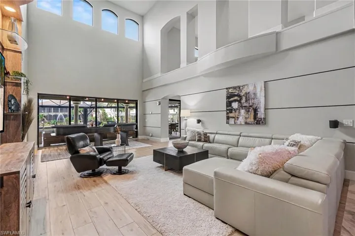 Two-story living area featuring wood-finish flooring, a wall of windows, and arched transom windows