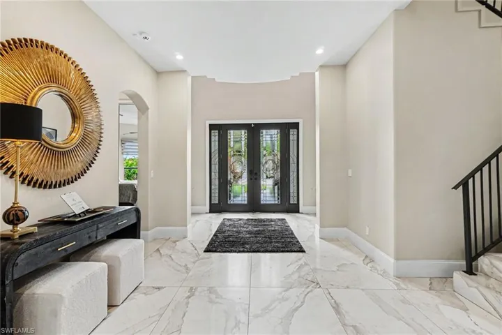 Grand entry foyer featuring large format marble-look tile flooring and a double-door entry with decorative glass inserts
