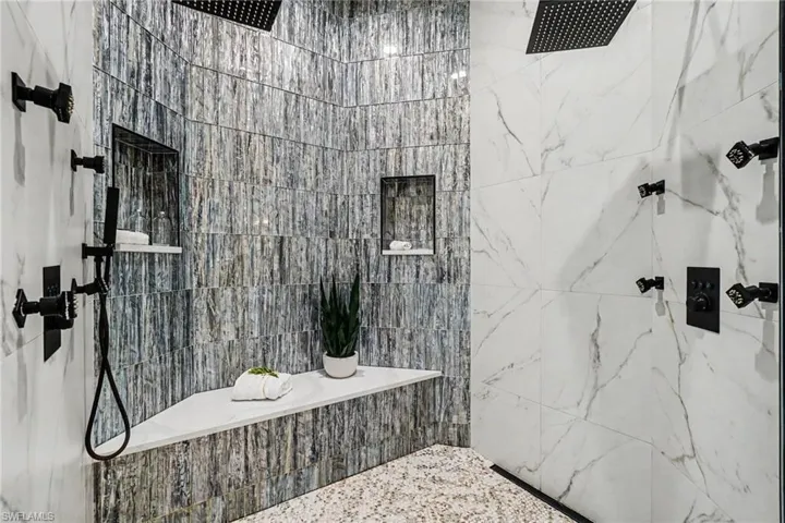 Spacious shower featuring multi-textured wall tiles and large-format white tile with gray veining