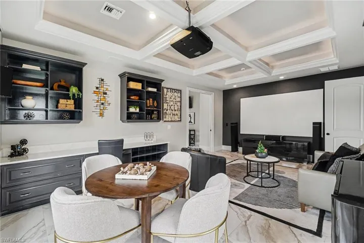 Entertainment room with a coffered ceiling, built-in cabinetry, and a large projection screen