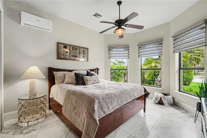 Bright room featuring large windows, white marble-look flooring, and a ceiling fan with integrated lighting