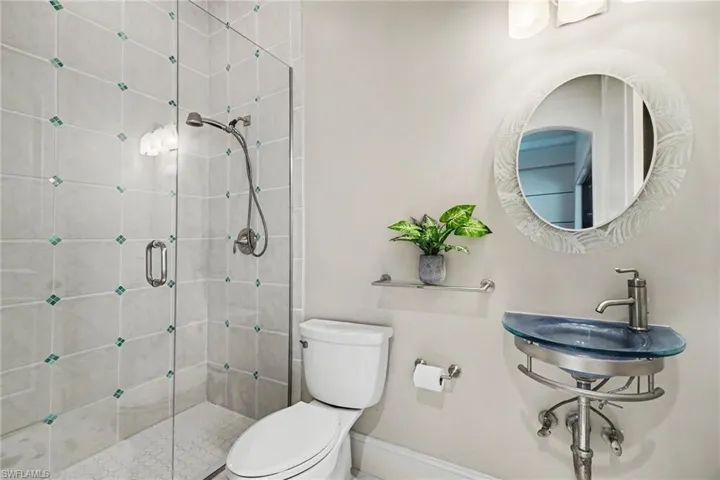 Bathroom featuring a glass-enclosed shower with tiled walls and a hex-tile floor