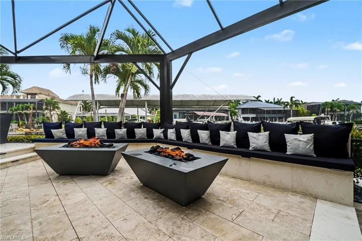 Outdoor living area featuring two modern fire pits, built-in bench seating, and travertine tile flooring