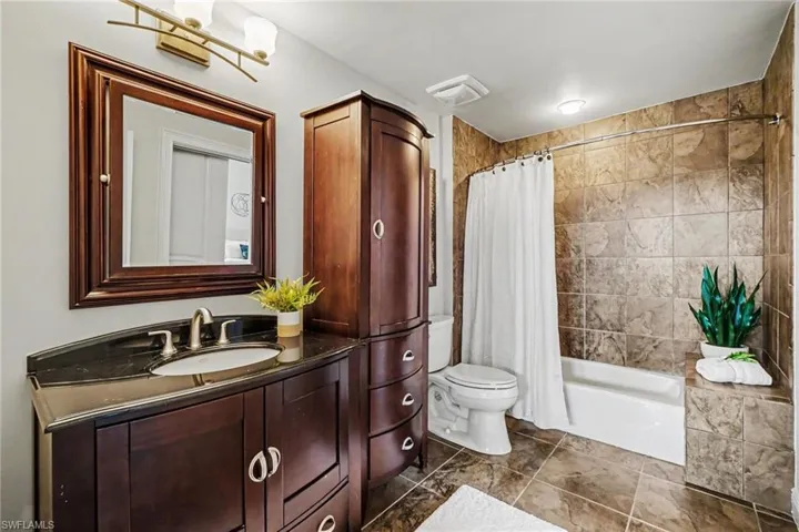 Bathroom featuring a dark wood vanity with a black countertop, rectangular undermount sink, and brushed nickel faucet