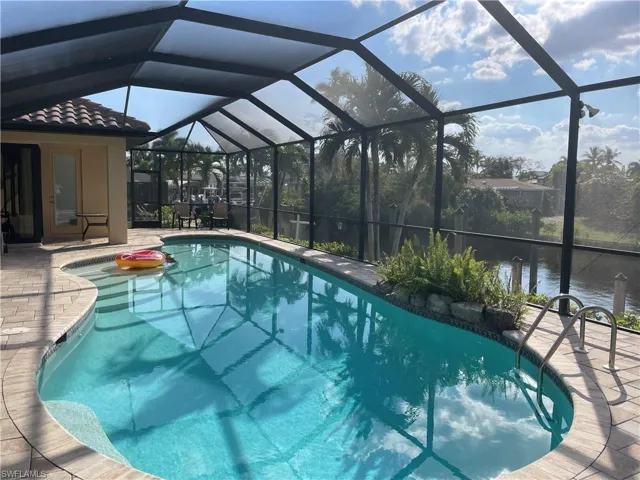 View of pool with glass enclosure and a patio