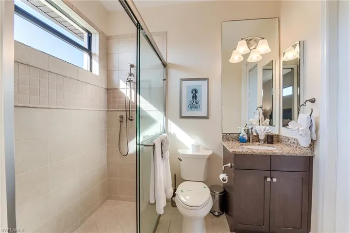 Bathroom featuring tile patterned floors, vanity, an enclosed shower, and toilet