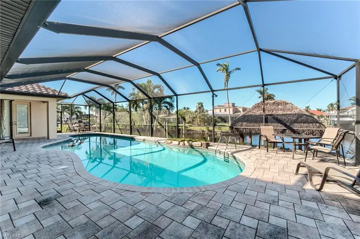 View of pool featuring glass enclosure, a patio area, and a water view