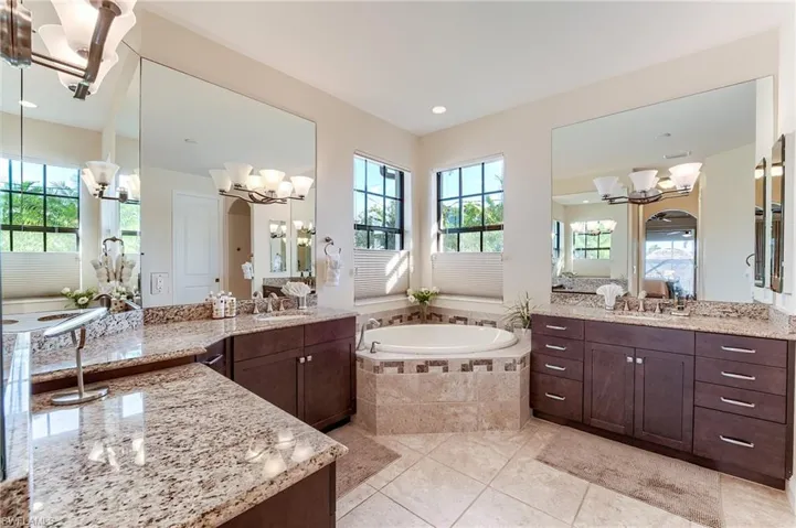 Bathroom with tile patterned flooring, vanity, and tiled bath