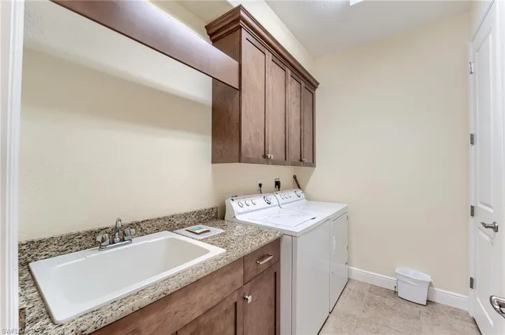 Washroom with cabinets, independent washer and dryer, light tile patterned floors, and sink