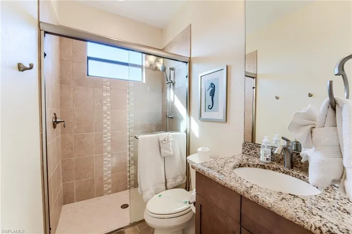 Bathroom featuring walk in shower, vanity, and toilet