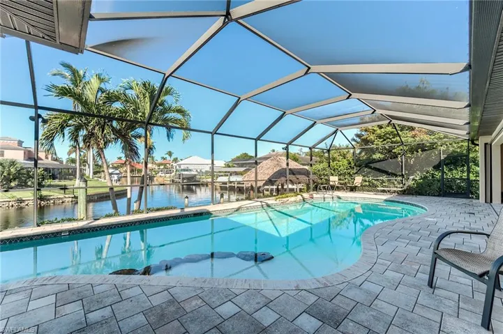 View of swimming pool with glass enclosure, ceiling fan, and a patio area