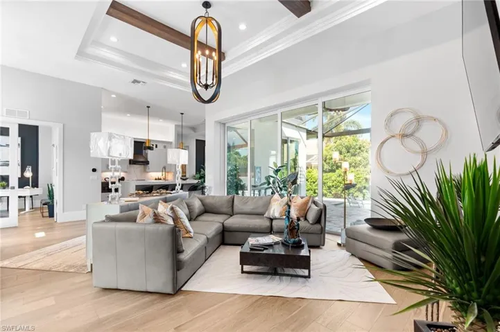 Living area featuring a tray ceiling, light wood finished floors, recessed lighting, and ornamental molding