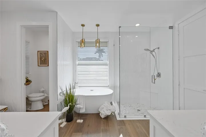 Full bathroom featuring vanity, a stall shower, a soaking tub, dark wood-style flooring, and tile walls
