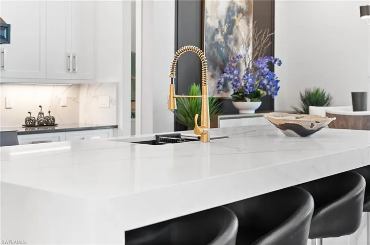Kitchen view of a kitchen bar, white cabinets, and dark stone countertops