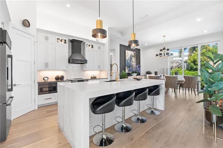 Kitchen featuring decorative backsplash, white cabinetry, recessed lighting, a breakfast bar area, and stainless steel refrigerator