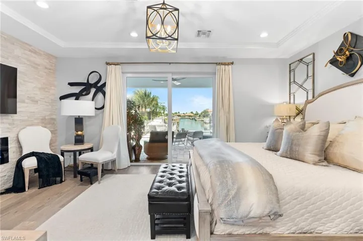 Bedroom with wood finished floors, recessed lighting, access to exterior, a water view, and ornamental molding