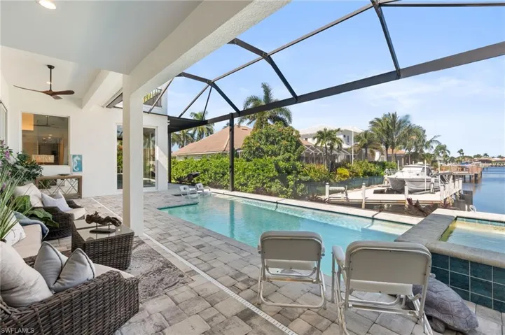 Outdoor pool with a patio area, a sunroom, glass enclosure, a water view, and an outdoor hangout area
