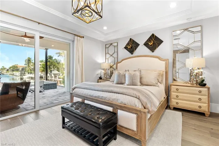 Bedroom featuring wood finished floors, recessed lighting, access to outside, crown molding, and a water view