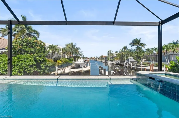 View of pool featuring a lanai, a water view, a pool with connected hot tub, a dock, and a sunroom