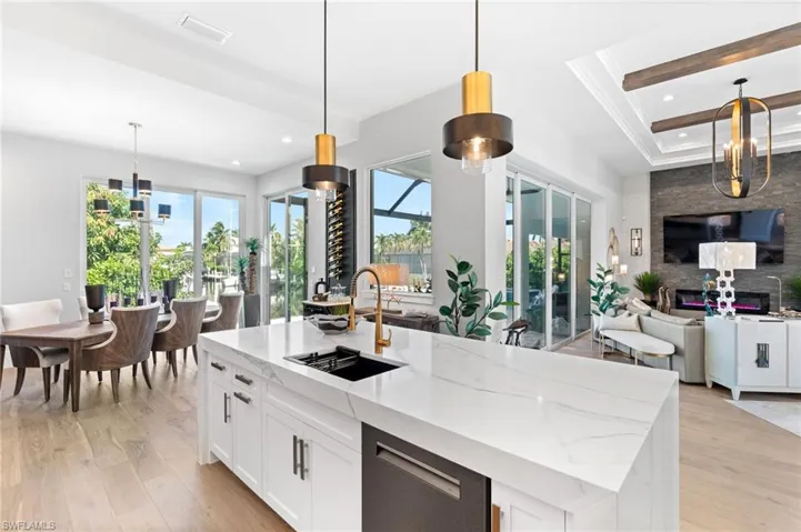 Kitchen featuring a chandelier, hanging light fixtures, white cabinetry, light stone countertops, and light wood-style floors