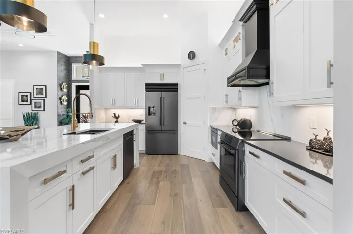 Kitchen with white cabinets, black appliances, dark stone countertops, light wood-style floors, and recessed lighting