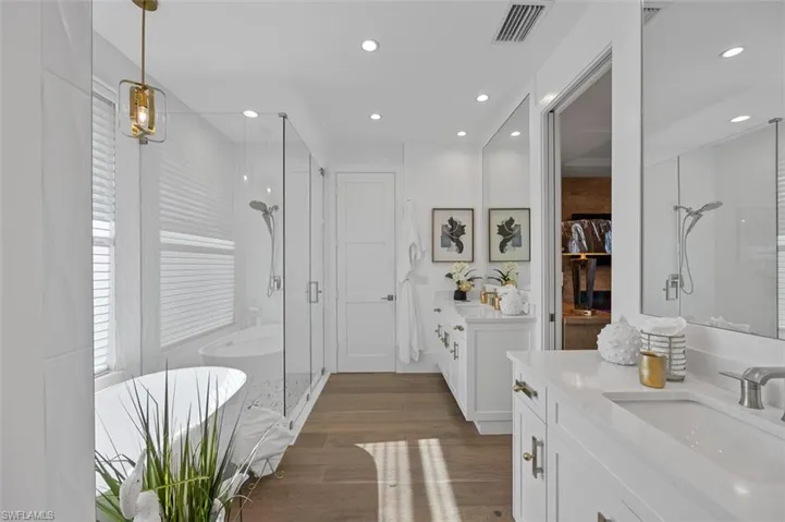 Bathroom with a stall shower, dark wood-type flooring, vanity, a freestanding tub, and a closet